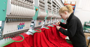 Technician preparing red workwear garments on a Tajima embroidery machine, showcasing high-quality embroidery production in a professional embroidery workshop.