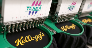 Close-up of Tajima embroidery machines stitching the Kellogg’s logo in golden thread onto black fabric, showcasing high-quality branded embroidery in progress.