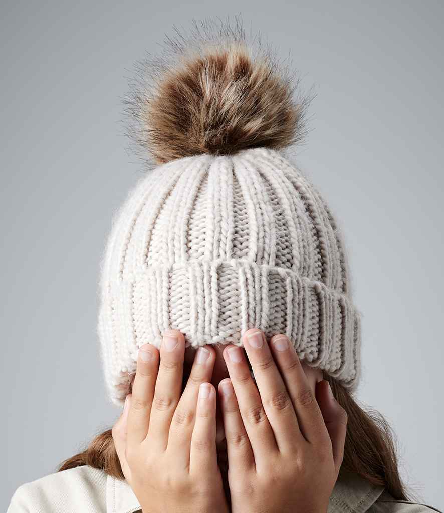 Beechfield Junior Faux Fur Pom Pom Chunky Beanie in ONE Oatmeal by Beechfield — Custom branded clothing by Print Press, featuring premium embroidery produced in our specialist print lab in the UK.