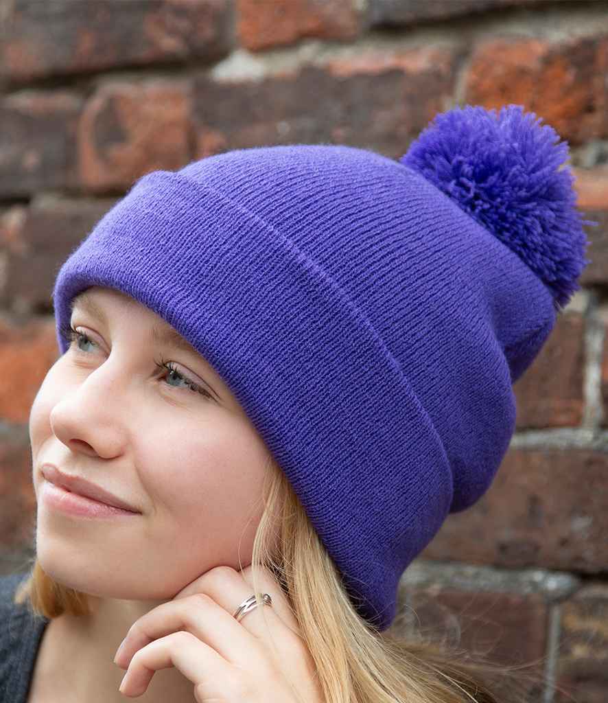 Result Core Pom Pom Beanie in ONE Purple by Result Winter Essentials — Custom branded clothing by Print Press, featuring premium embroidery produced in our specialist print lab in the UK.
